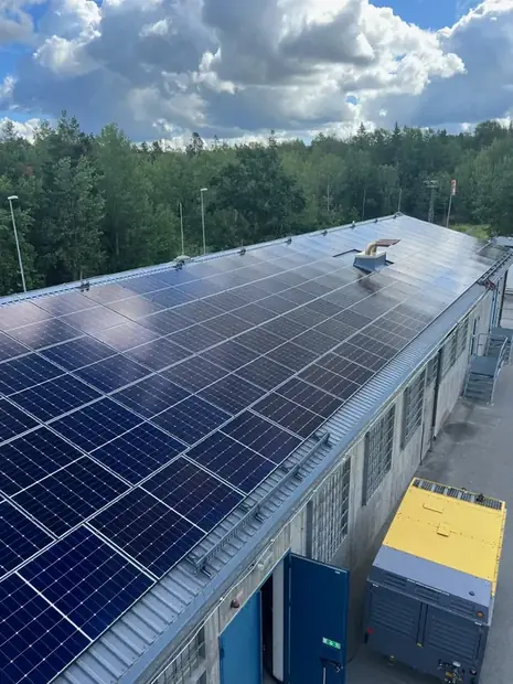 Långsträckt industritak med solpaneler i rader längs hela takfallet.