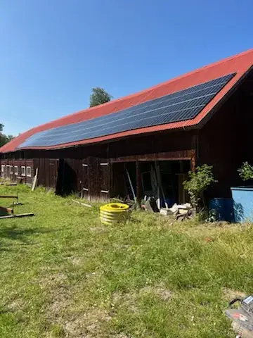 Röd ladugård med solpaneler monterade på det röda tegeltaket.