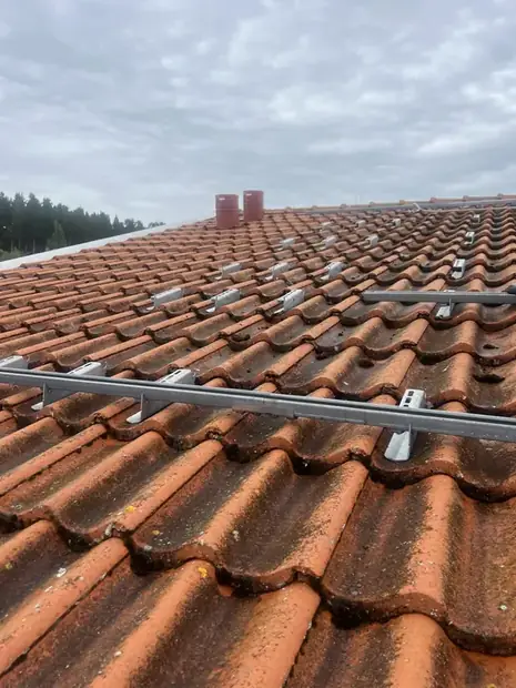 Aluminiumskenor monterade över ett tegeltak inför panelmontage.